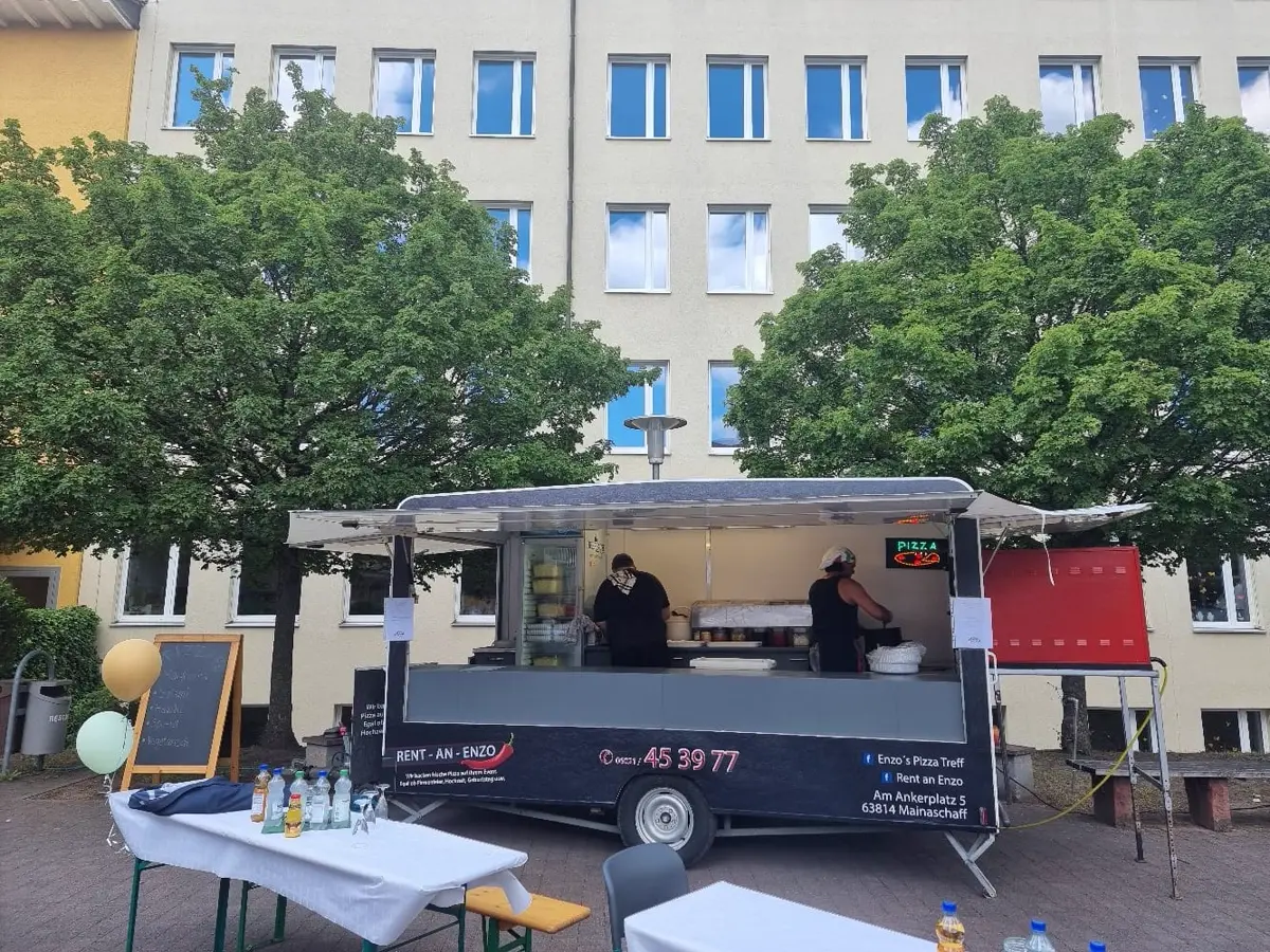 Pizza-Anhänger vor einem Firmengebäude mit Sitzbereich