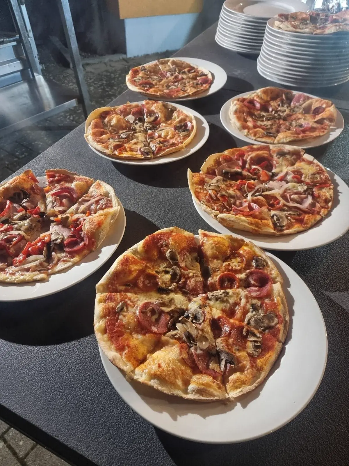 Mehrere frisch gebackene Pizzen auf Tellern