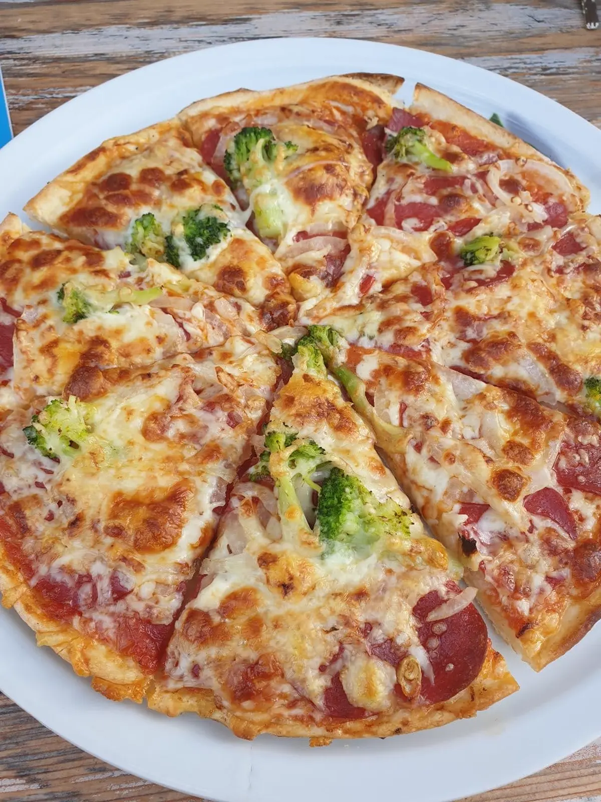 Aufgeschnittene Pizza mit gemischtem Belag und Basilikum