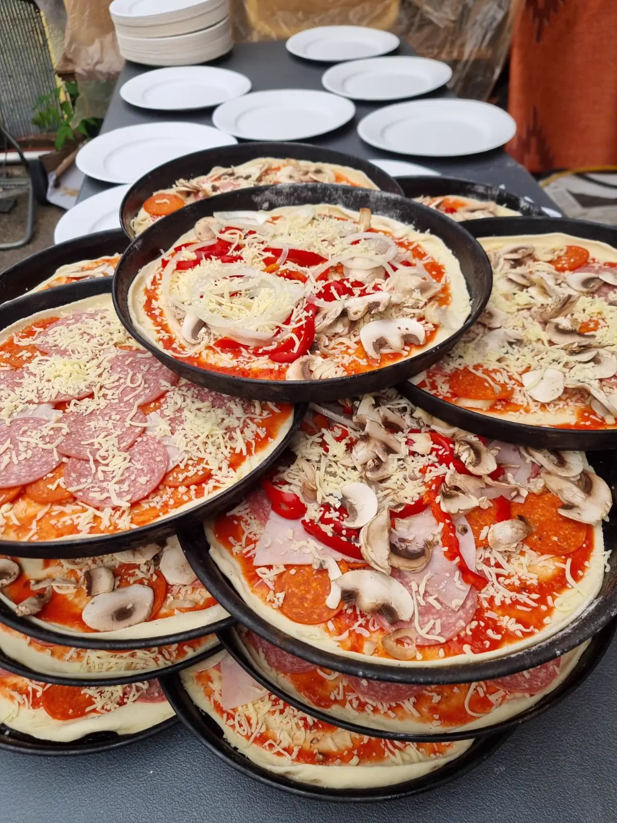 Mehrere vorbereitete Pizzen auf Blechen